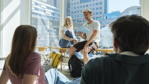Personen sitzen im Foyer am Campus und unterhalten sich