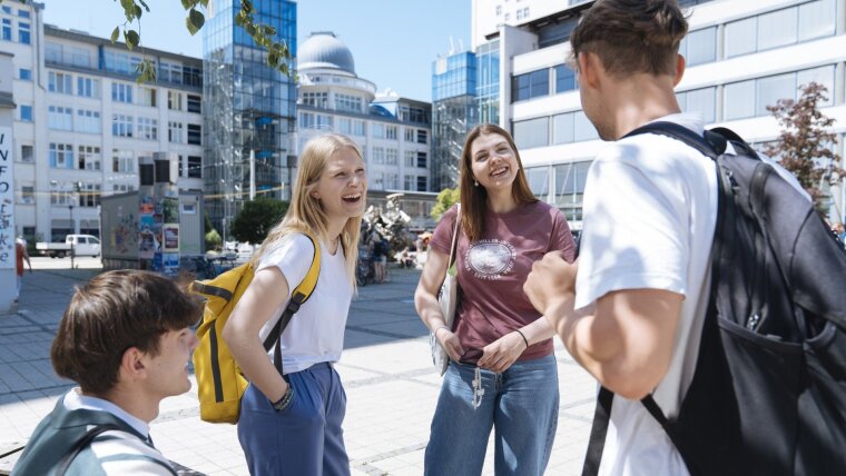 vier Personen stehen auf dem Campus und unterhalten sich