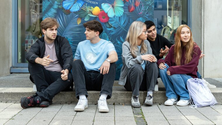 Junge Menschen sitzen nebeneinander und erzählen