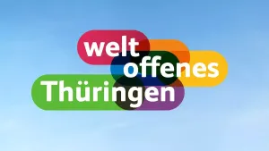 Der Claim »weltoffenes Thüringen« steht als buntes Logo vor blauem Himmel