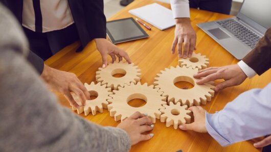 Mitarbeiter fügen Zahnräder als Metapher für Teamarbeit und Arbeitslösungen zusammen